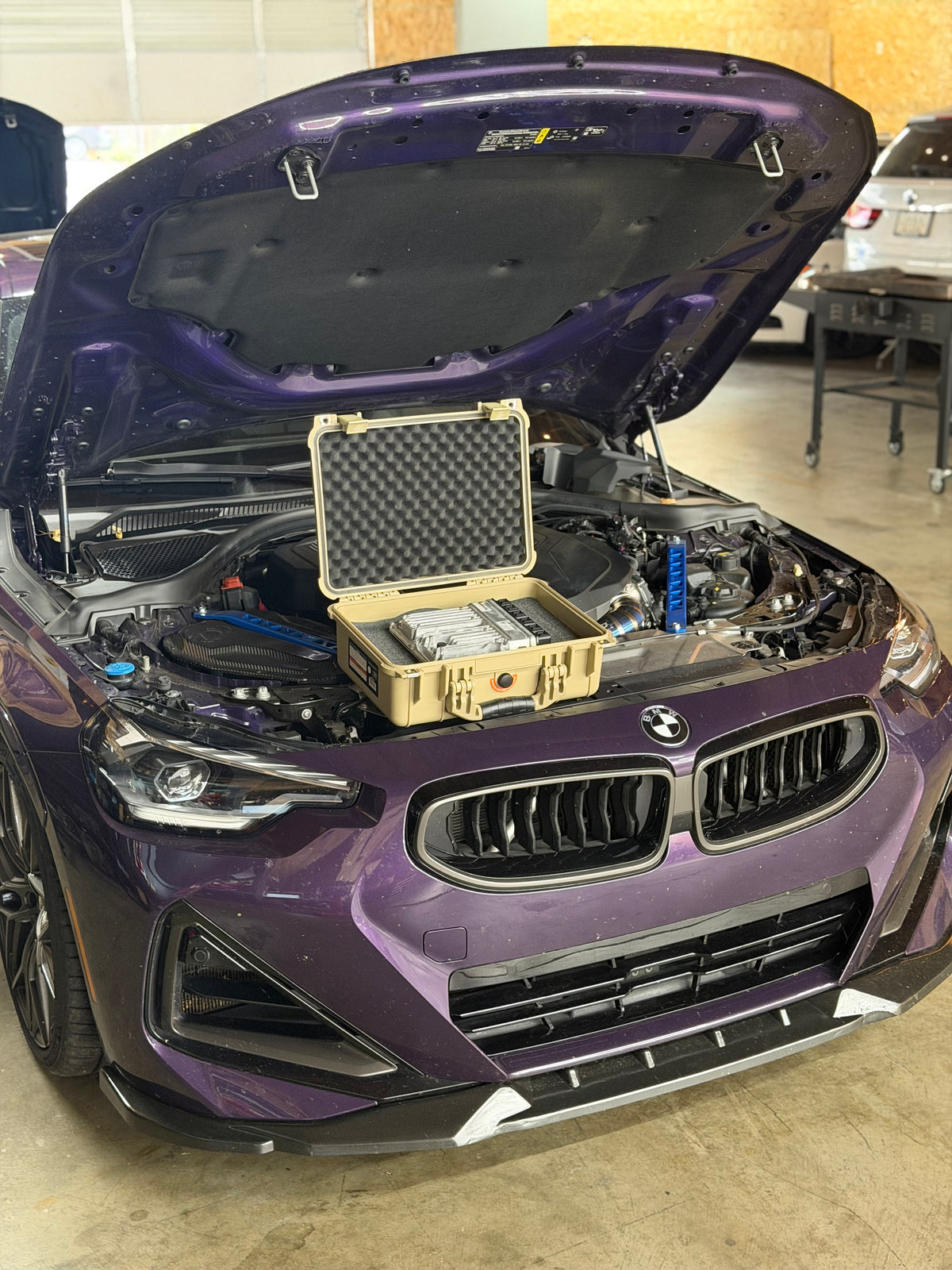 Purple BMW with its hood open in the workshop